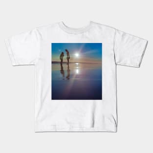 Silhouetted people in a row on a sand beach. Kids T-Shirt